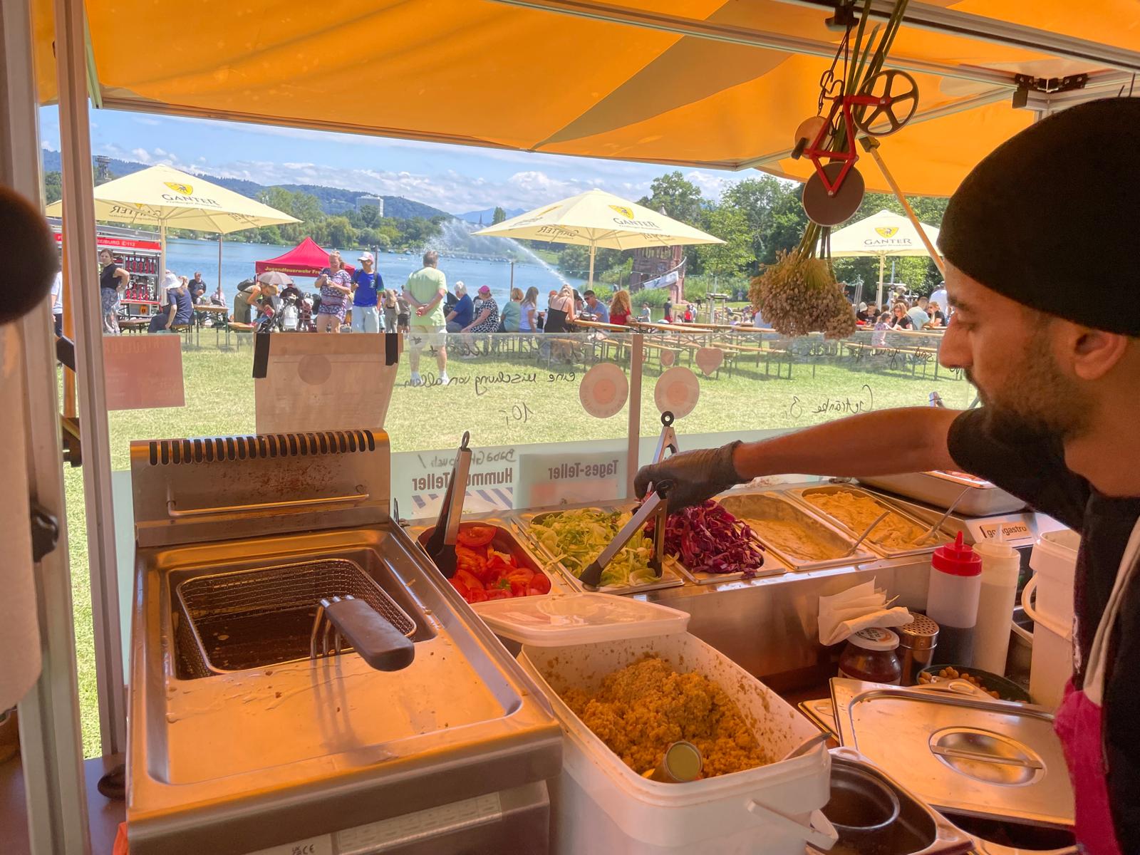 Koch bereitet Falafel-Teller in der mobilen Küche am Seeufer zu